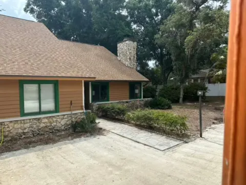 Graded limerock drive beside a single story building with a stone chimney