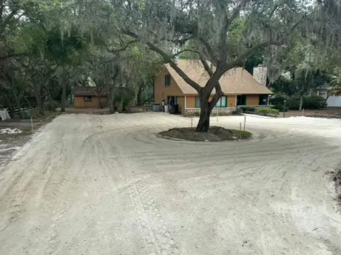 Graded circular drive around a large oak tree in front of a house