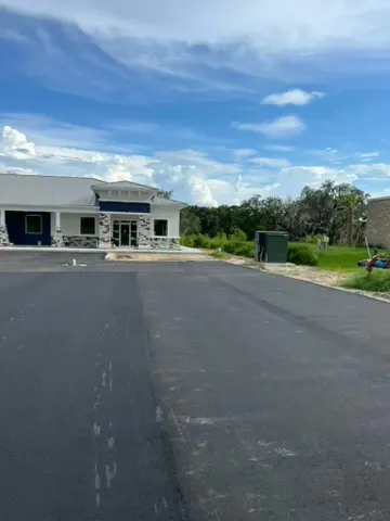 New asphalt drive and parking area in front of a light colored commercial building