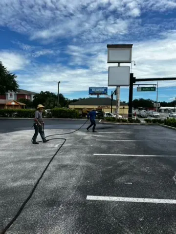 Dark sealed parking lot with crisp white stall lines in front of a retail building