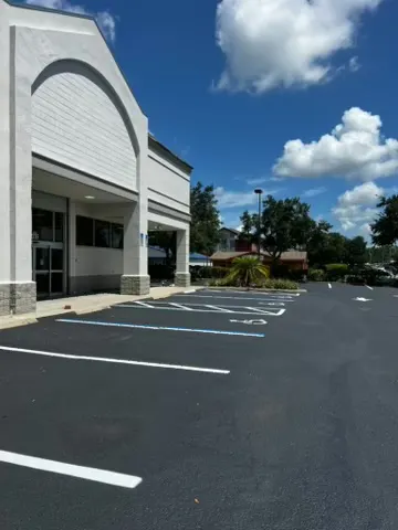 Crew member walking a striping machine across a paved parking lot