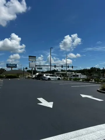 Wide stretch of new black asphalt across a commercial parking area