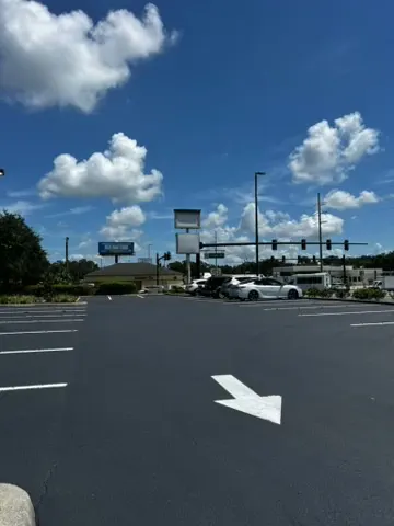 Freshly paved commercial parking lot with white directional arrow and parking stalls