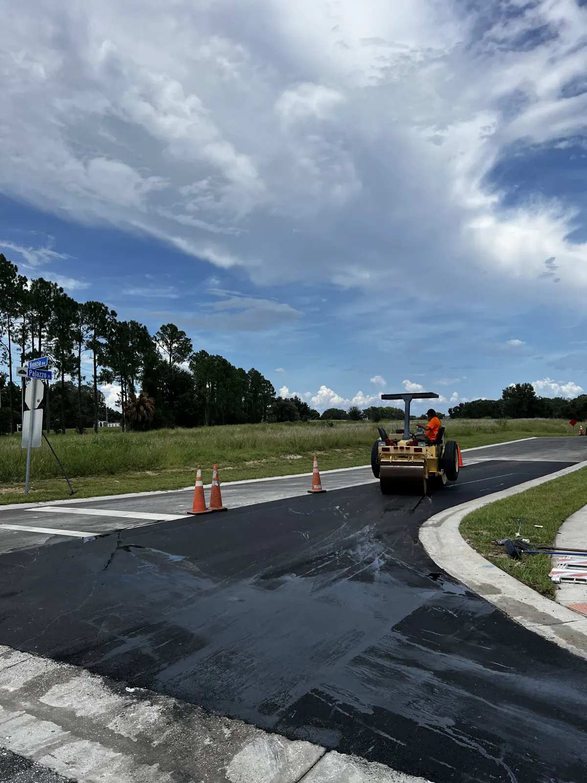 Operator on a roller compacting fresh asphalt at a road intersection