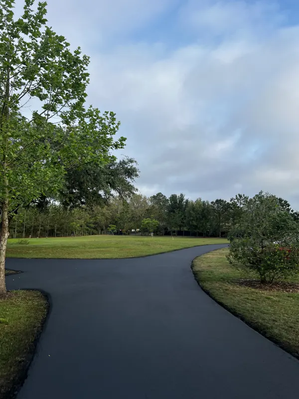 New asphalt driveway curving through a lawn