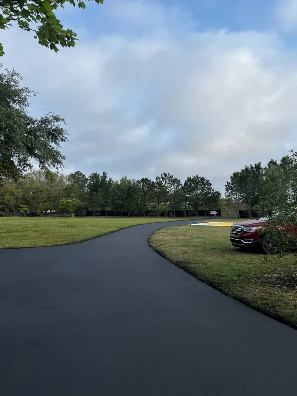 New asphalt driveway bending past a parked truck