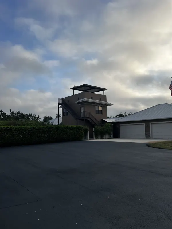 New asphalt motor court in front of a multi level house and garage