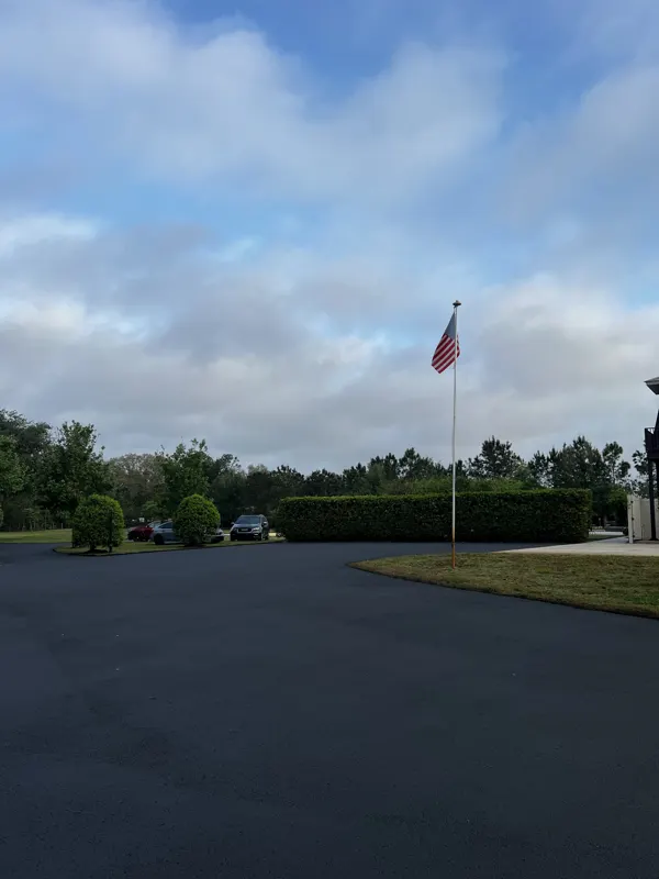 New asphalt motor court with a flagpole and hedges